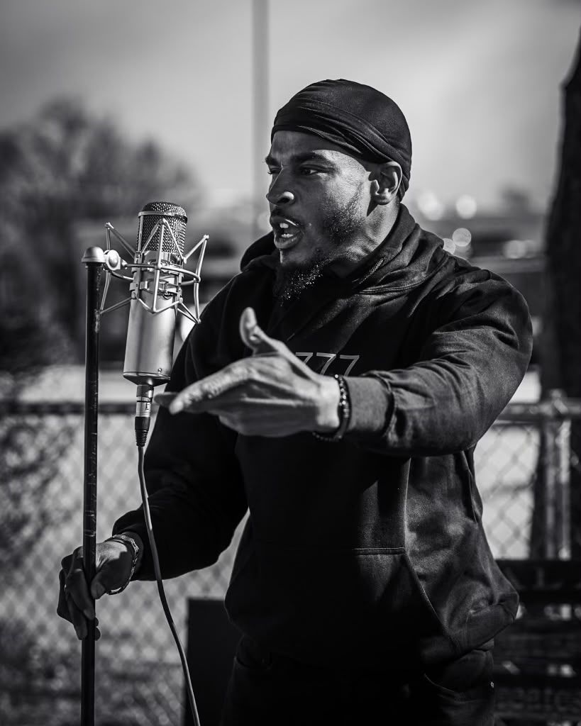 Silent 777 rapping into a microphone outdoors in black and white.